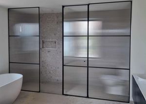 ShowerScreens_10mmDesignerFramed_Pivot_NarrowReed_Fluted_Glass_Black_Frame_Hardware